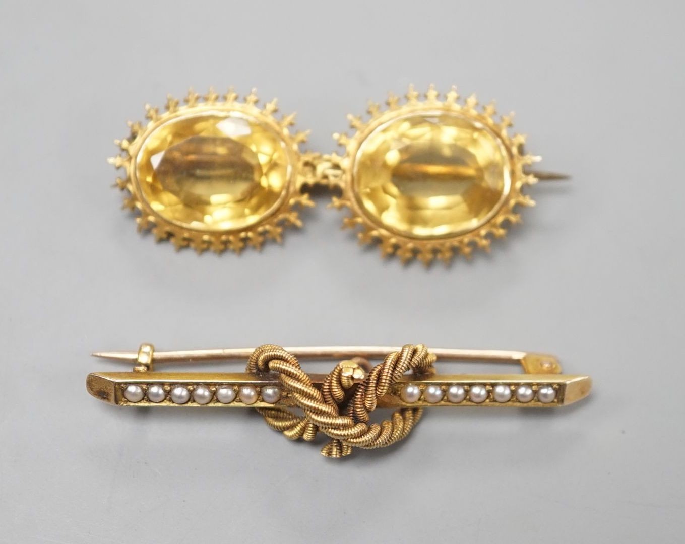 An Edwardian 15ct and seed pearl set rope twist bar brooch, 42mm and a yellow metal and two stone citrine set bar brooch, gross weight 8.3 grams.